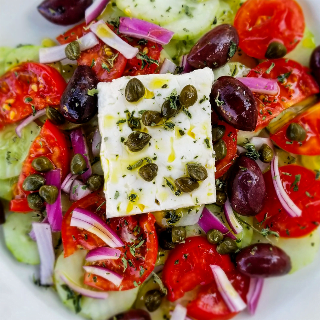 Greek Food - Horiatiki Salata: Rustic symphony of tomatoes, olives, and feta.